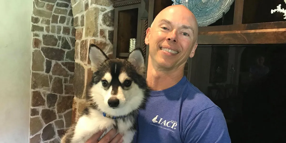 Dallas dog trainer holding a young Husky after a successful in-home training session.